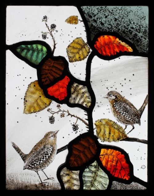 wrens in brambles by ise stumpff, a stained glass panel featuring two small wrens and a bramble branch with leaves in green, red white and gold.